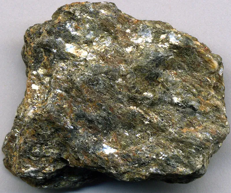 Hand sample of muscovite schist with a silvery, foliated surface