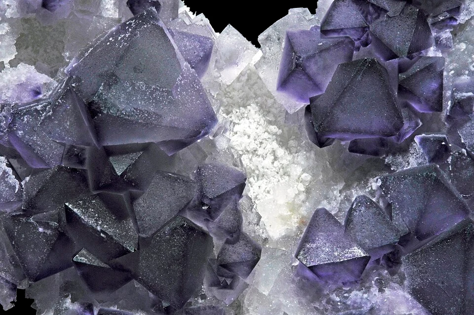 Cluster of cubic green and purple fluorite crystals with calcite on a rock matrix