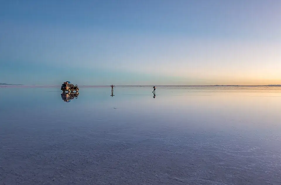 Vast white salt crust of Salar de Uyuni stretching to mountains on the horizon at sunrise