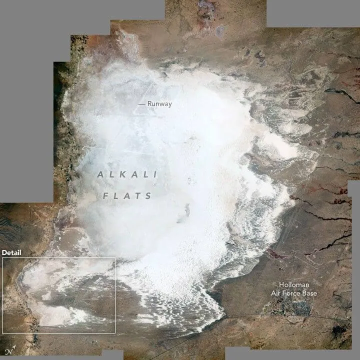 Astronaut photograph of the brilliant white gypsum dune field of White Sands National Park contrasting with darker desert terrain.