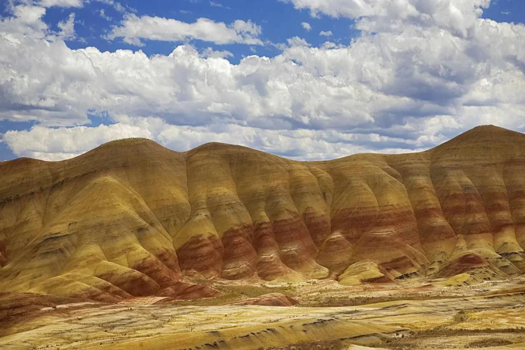 Colinas estratificadas de colores bajo un cielo parcialmente nublado (litificación)