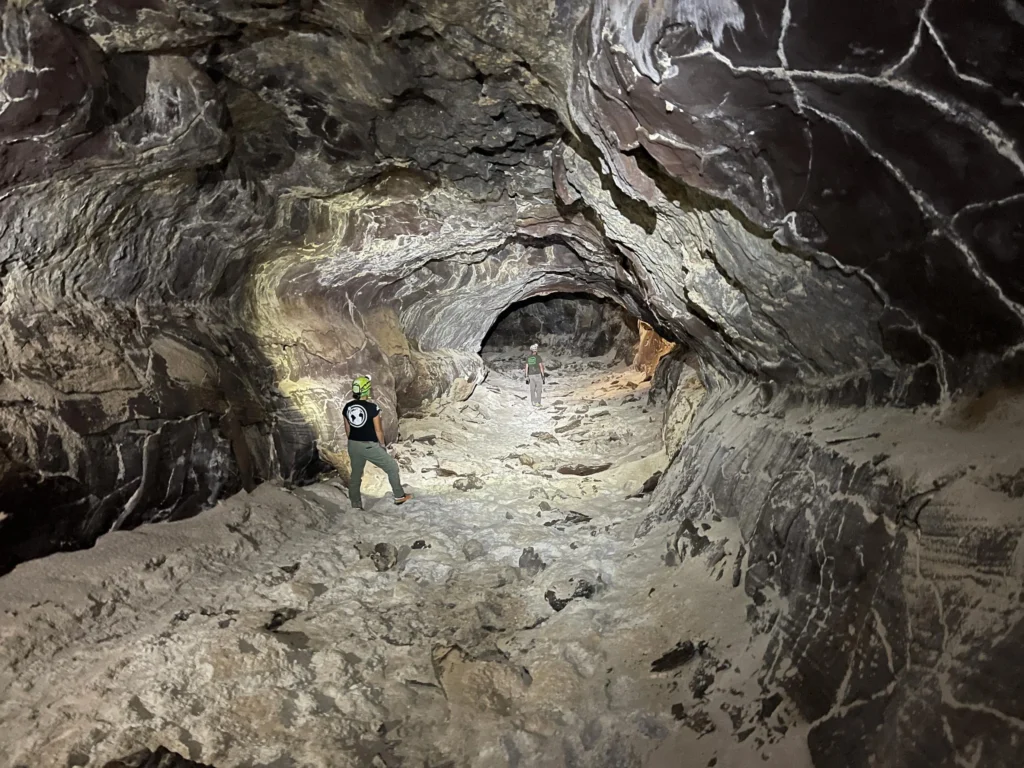 Personas que exploran un túnel rocoso en una cueva (tubo de lava)
