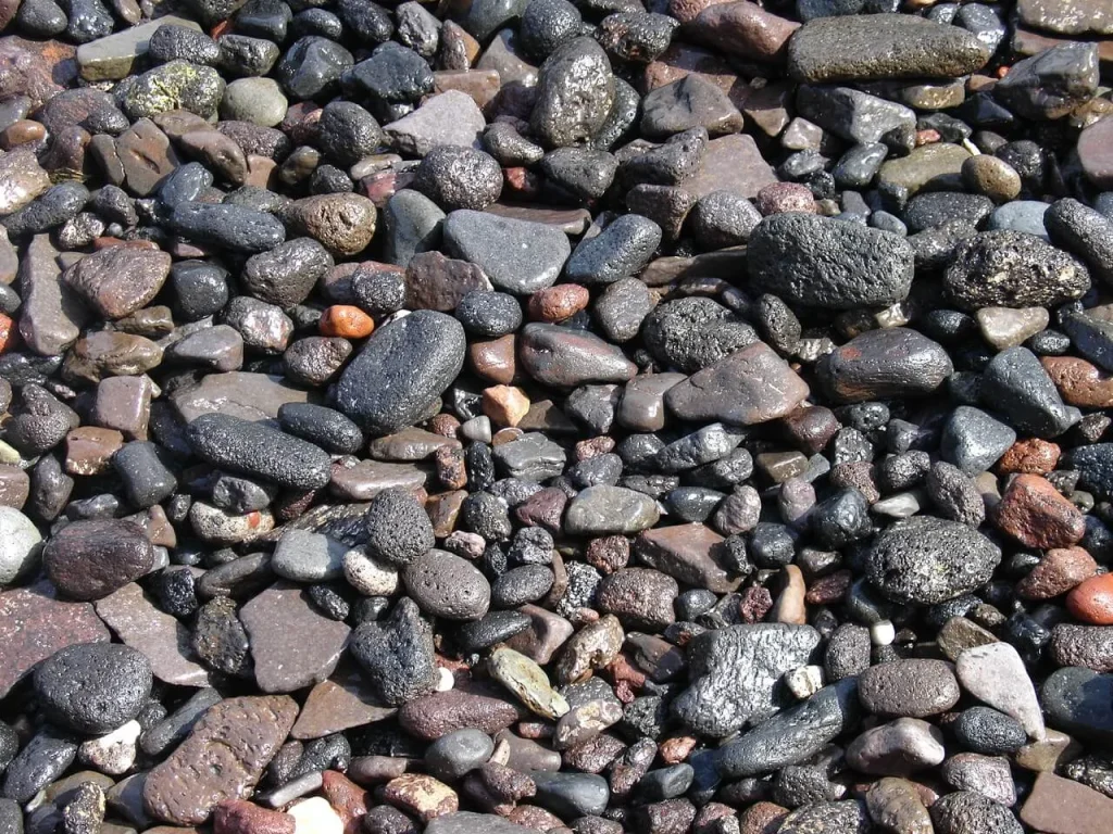 Cantos y piedras oscuros y mojados en una playa (material no consolidado)