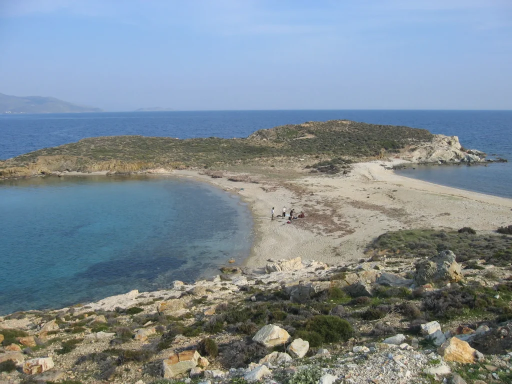 Playa rocosa con un mar azul y transparente y una península (tómbolo)