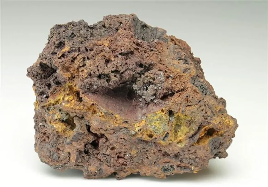 Muestra de roca volcánica porosa de color pardo y amarillo (gossan)