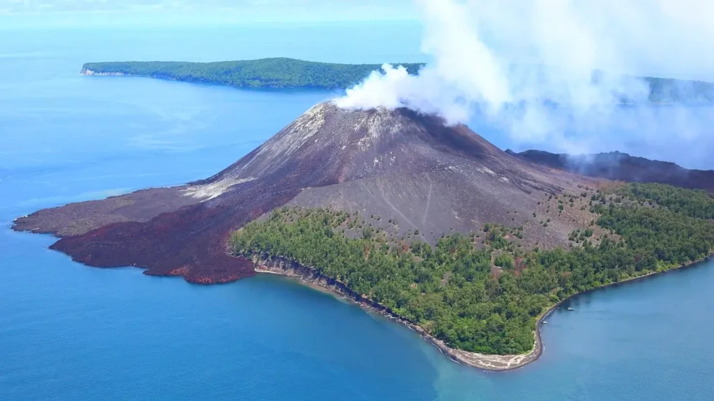 Isla volcánica humeante rodeada de océano azul (Krakatoa)