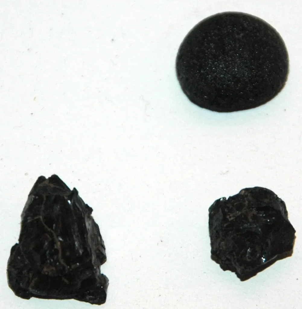 Group of black billitonite tektites with rough pitted surfaces, sub-equant and splash-form shapes, from Belitung Island, Indonesia