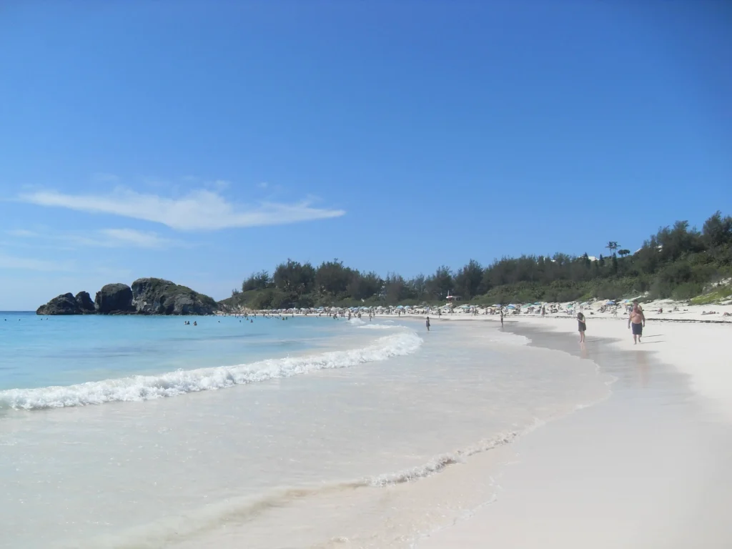 Horseshoe Bay beach in Bermuda, a curve of pale pink sand between dark volcanic rock outcrops and turquoise water.