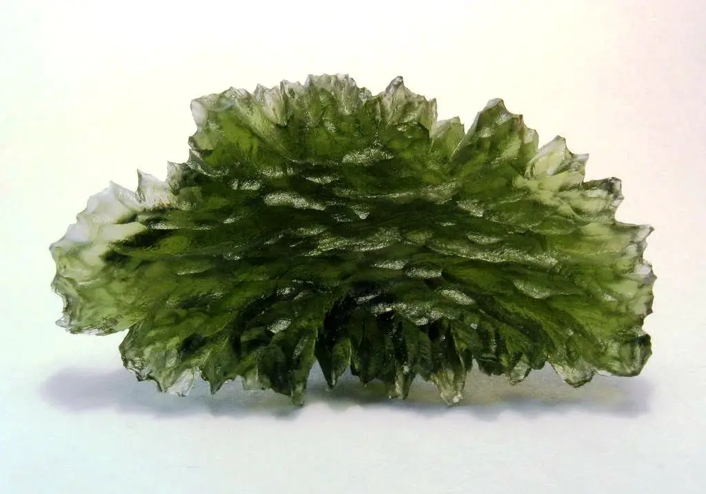 Translucent bottle-green Besednice moldavite with deeply etched hedgehog-like surface texture, on a black background