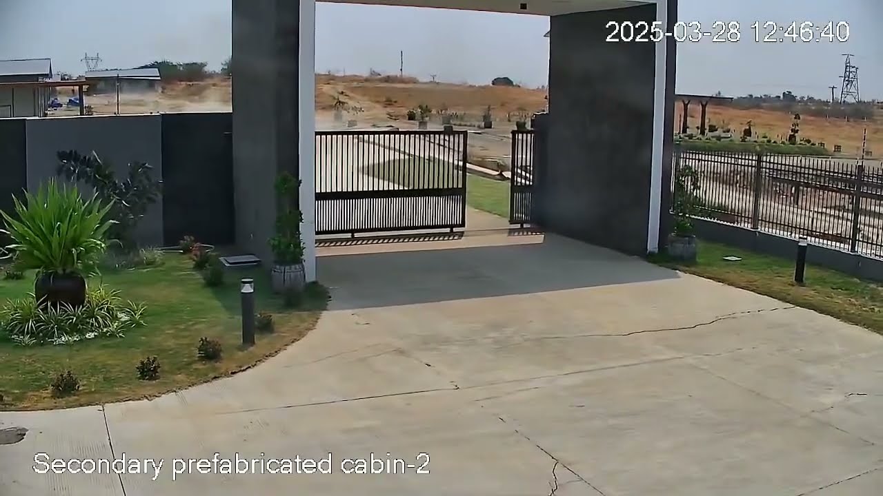 Still frame from the Tha Pyay Wa CCTV security camera showing the concrete-and-metal gate, driveway, and distant hills moments before the 28 March 2025 Sagaing Fault rupture passed through the frame.