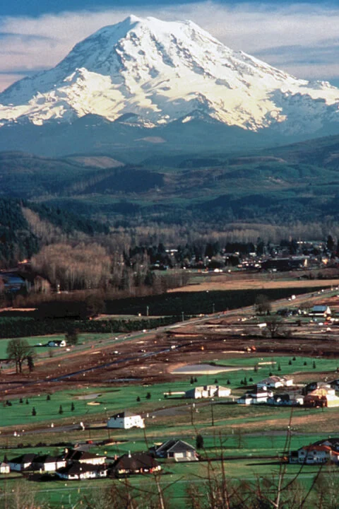 Mount Rainier seen rising behind the small Pacific Northwest town of Orting, Washington, which sits on the floor of the Puyallup River valley directly atop deposits of the 1507 Electron Mudflow.