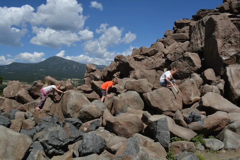 A mounded pile of rounded, rust-brown boulders forming the Ringing Rocks tor on a Montana hillside under a blue sky.