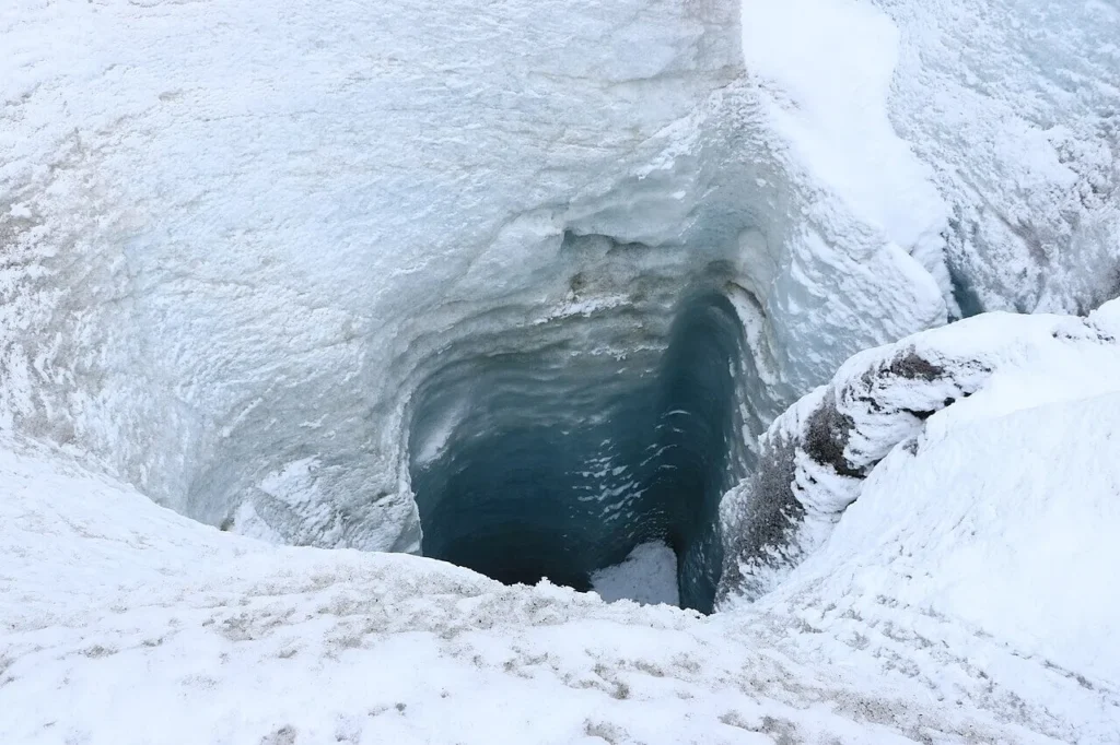 A moulin on the Athabasca Glacier, a roughly circular meltwater shaft of blue ice plunging down into darkness.