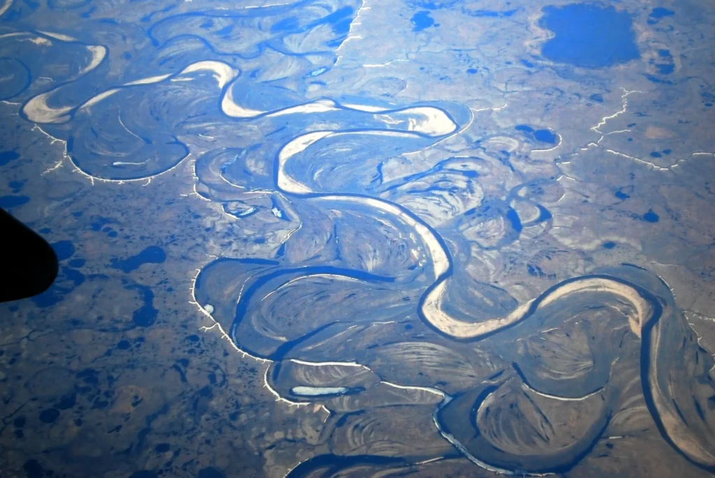 Aerial view of the flat, lake-pocked Yamal Peninsula tundra with a meandering river and an oxbow lake