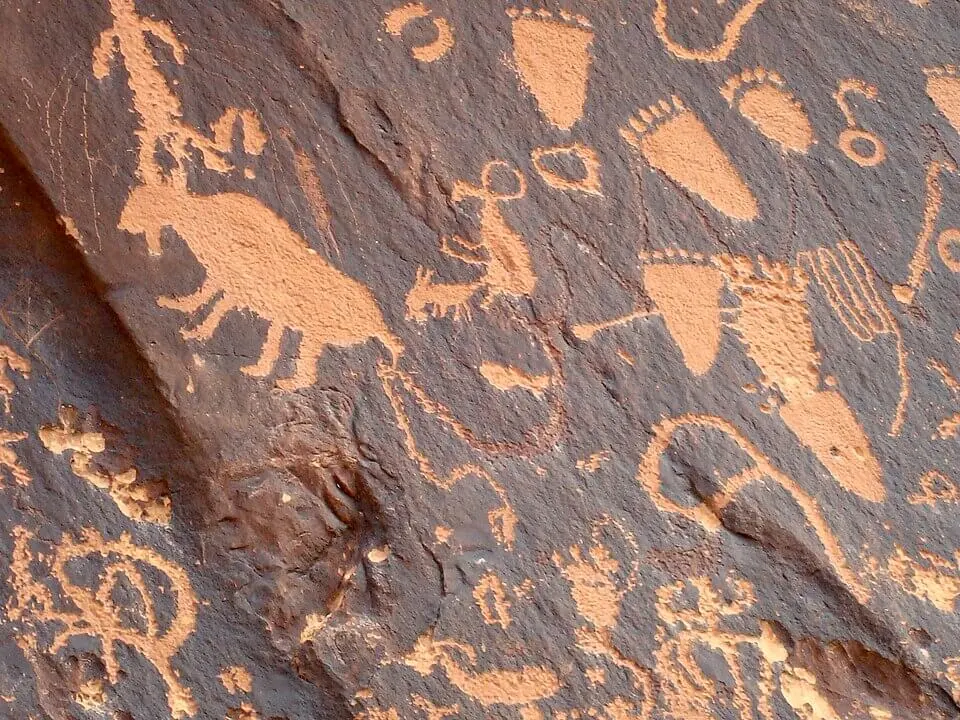 The Newspaper Rock petroglyph panel in Utah, with hundreds of figures pecked through dark desert varnish to expose the lighter sandstone beneath