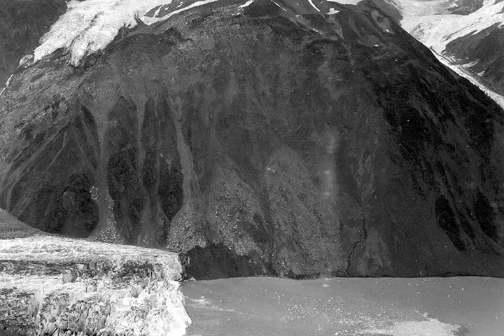 1958 photograph of the bare rockslide scar high on the steep northeast wall of Gilbert Inlet, where a slab of mountain broke loose and fell into Lituya Bay