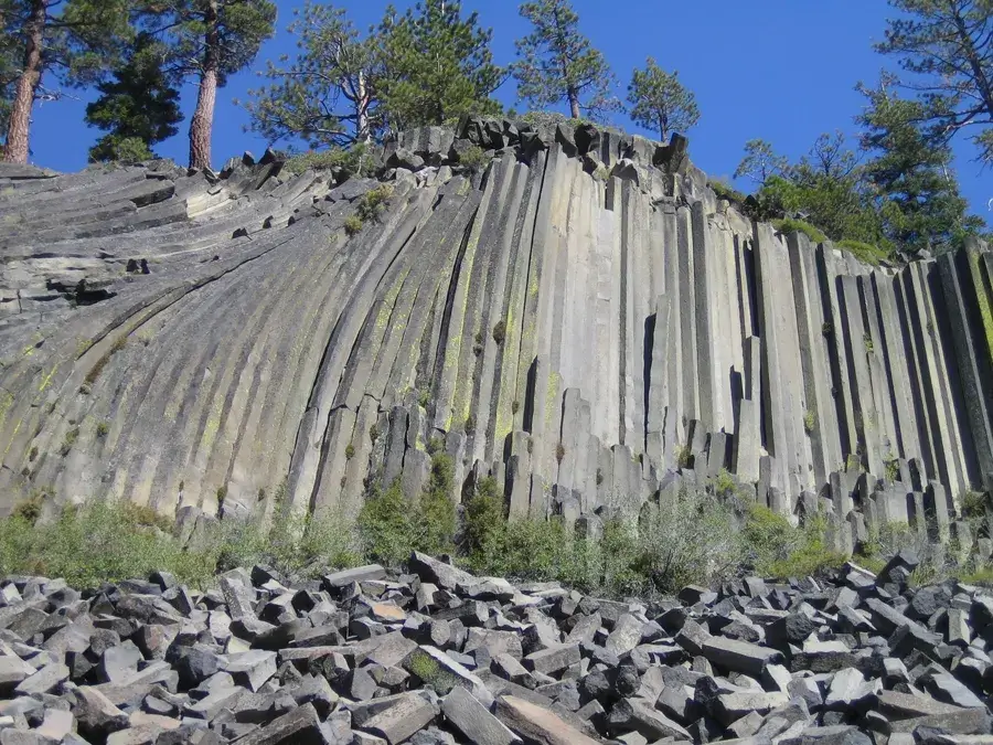 Tall vertical basalt columns at Devils Postpile with a talus pile of broken columns at the base.