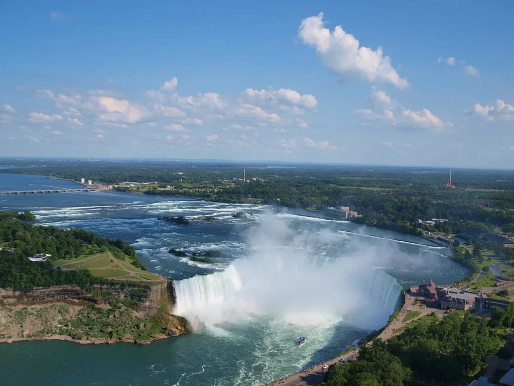 Aerial view of the curved Horseshoe Falls at Niagara with the city of Buffalo visible on the horizon