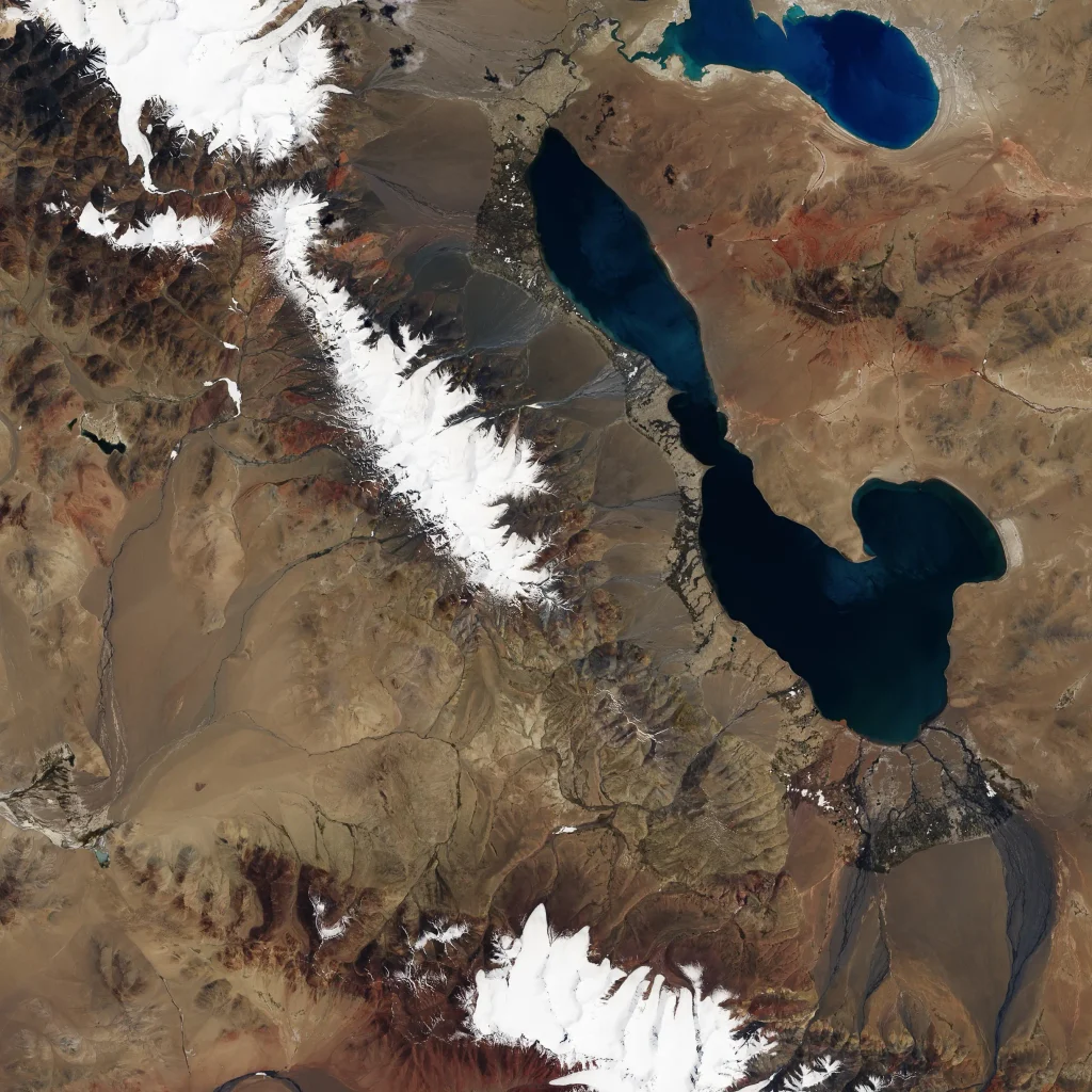 Satellite image of a pale grey ice and rock debris field spreading across a wide valley floor in the Aru Range, Tibet, after the July 2016 glacier tongue detachment.