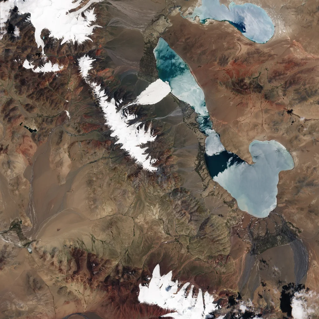 Satellite image of a pale grey ice and rock debris field spreading across a wide valley floor in the Aru Range, Tibet, before the July 2016 glacier tongue detachment.