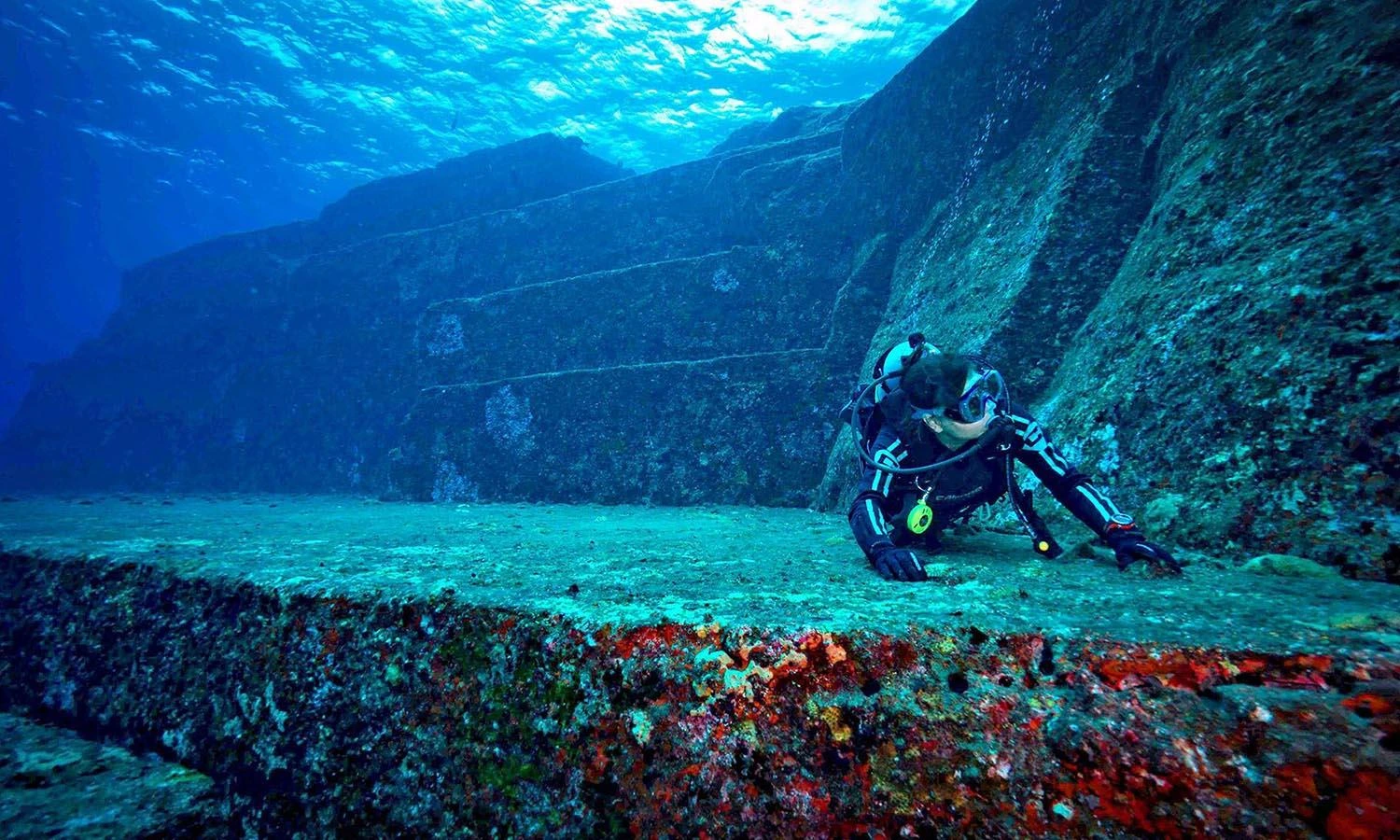 Diver exploring the stepped underwater rock formations of the Yonaguni Monument in Japan