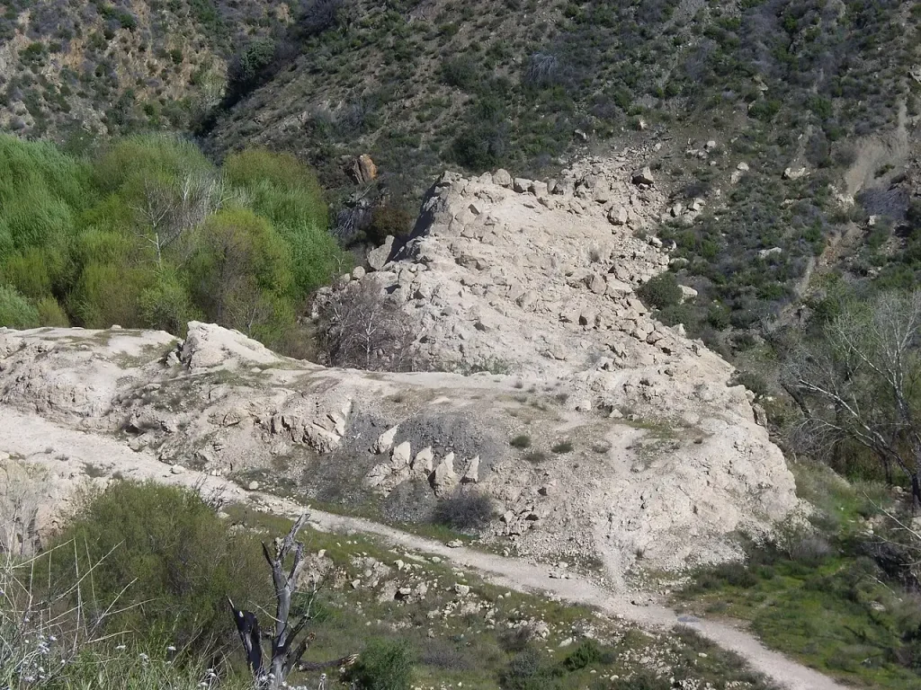 Weathered gray concrete rubble of the dam base among brush in San Francisquito Canyon