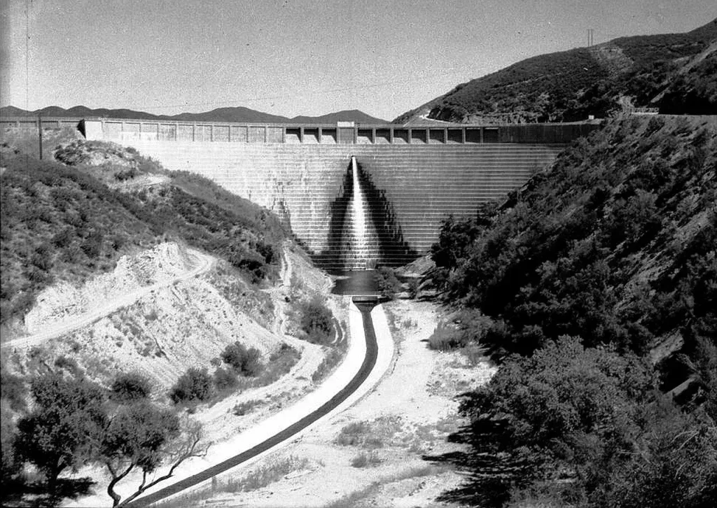 The completed St. Francis Dam seen from downstream, with its stepped face and the wing dike on the ridge